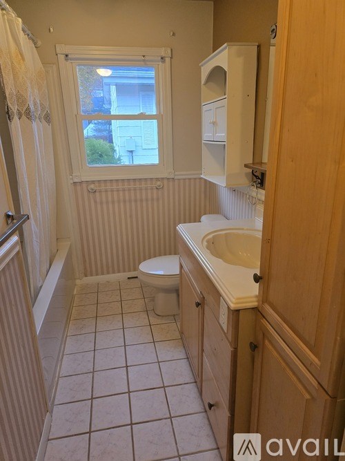 A bathroom with a toilet, sink, and window.