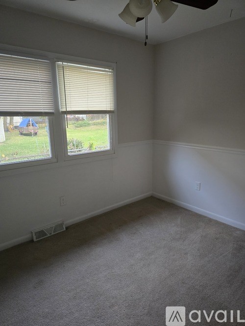 A room with a carpeted floor and a window with blinds.