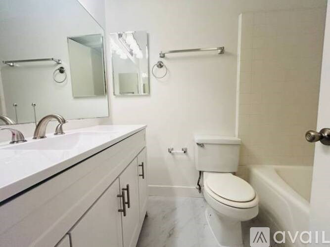 A white bathroom with a toilet, sink, and mirror.