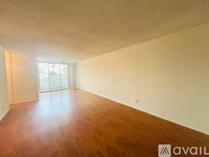 A room with wooden flooring and a window letting in sunlight.