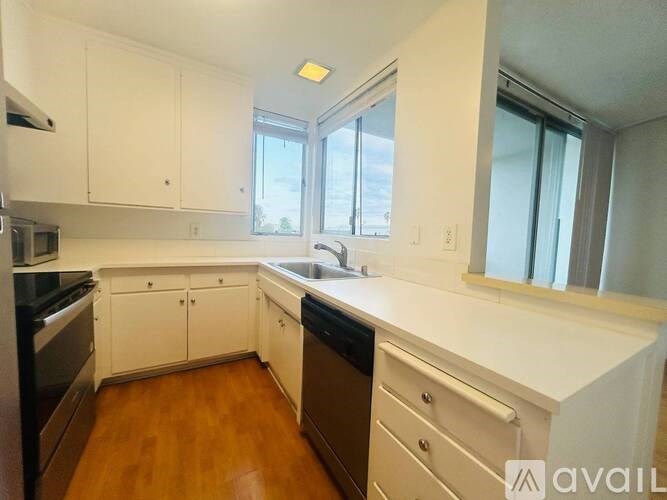 A kitchen with white cabinets and wooden floors.