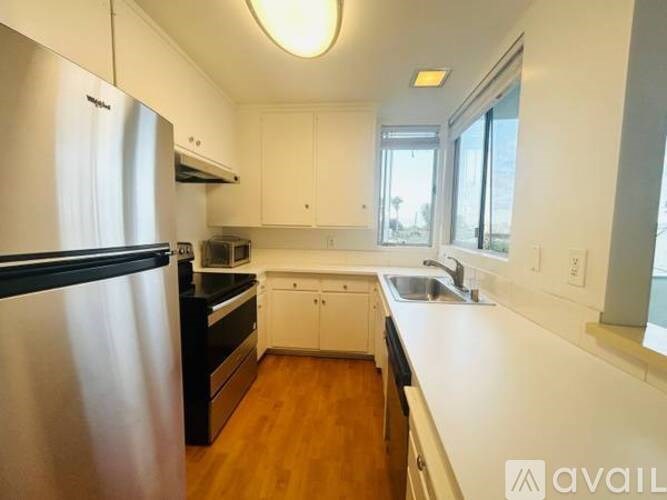 A kitchen with white cabinets and a stainless steel refrigerator.