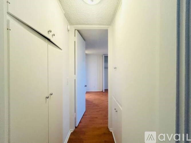 A long hallway with white walls and wood flooring.