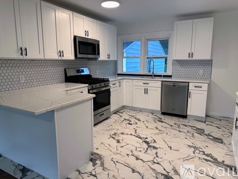 A kitchen with white cabinets and a black microwave above the stove.