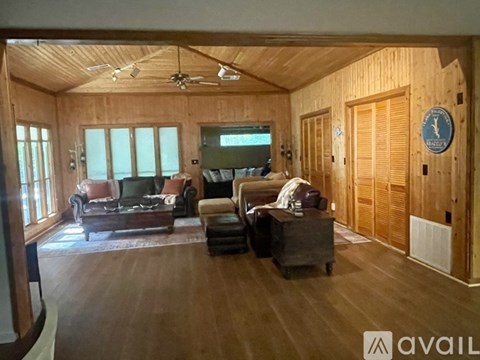 A living room with wooden walls and ceiling, furnished with a couch, chair, and ottoman.