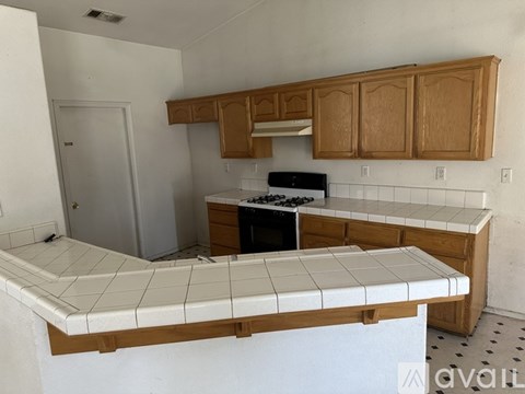 A kitchen with a white counter top and wooden cabinets.
