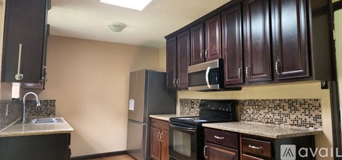 A kitchen with brown cabinets and a black refrigerator.