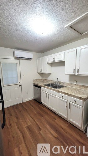 A kitchen with white cabinets and a wooden floor.