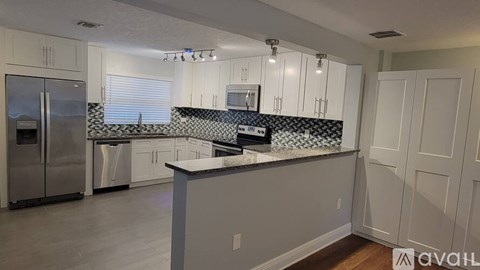 A kitchen with white cabinets and a black and white backsplash.
