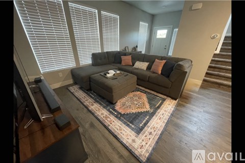 A living room with a grey couch and a rug in front of it.