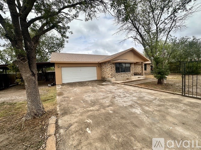 A house with a brown roof and a white garage door is surrounded by a black fence.