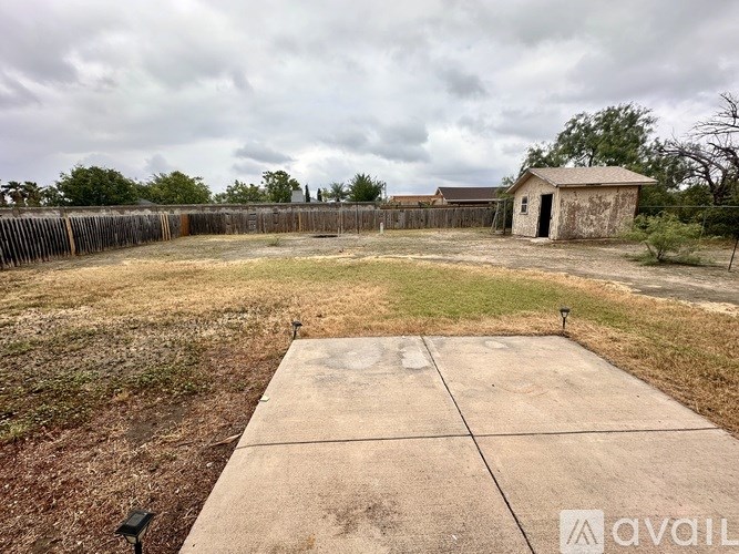 A concrete slab in the foreground with a fence and a shed in the background.