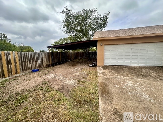 A backyard with a wooden fence and a covered patio area.