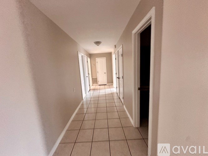 A long hallway with white walls and tile flooring.