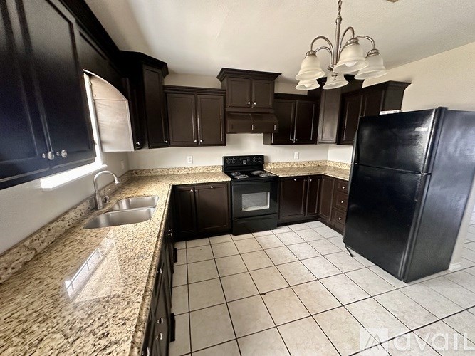 A kitchen with black cabinets and a granite counter.