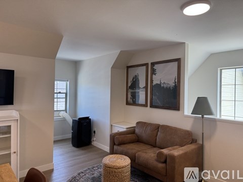 A living room with a brown couch and a black trash can.