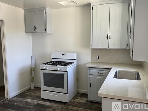 A kitchen with a white oven, sink, and cabinets.