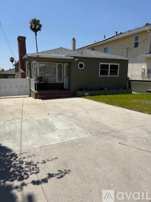 A house with a green front yard and a palm tree in the background.