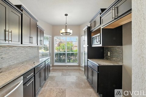 A kitchen with black cabinets and a hanging light fixture.
