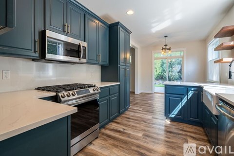 A kitchen with dark blue cabinets and a stainless steel stove.