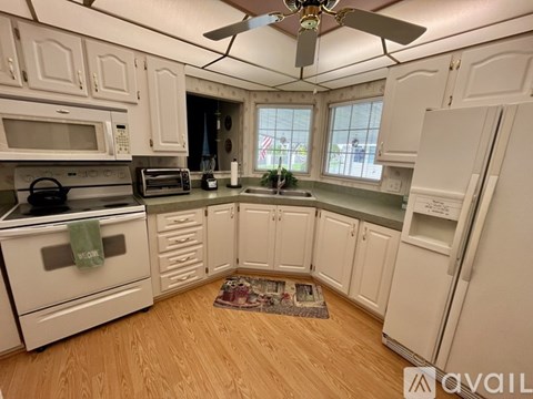 A kitchen with white cabinets and a wooden floor.