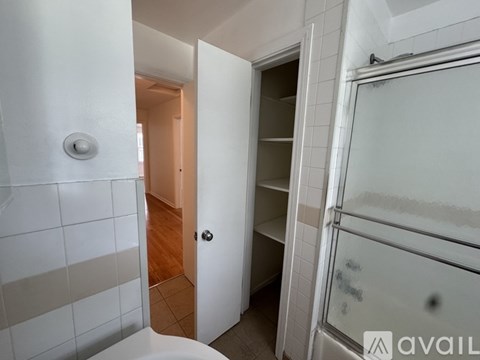A white bathroom with a glass shower door and a white tiled wall.