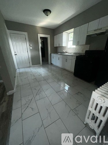 A kitchen with white cabinets and a black refrigerator.