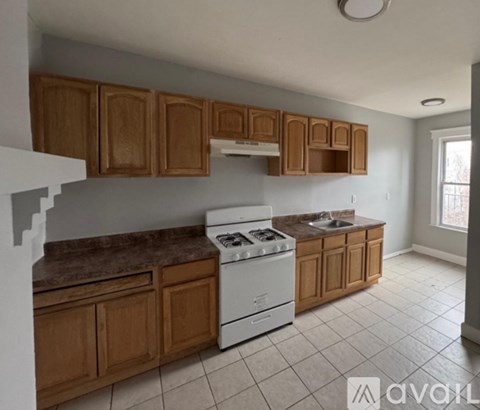 A kitchen with wooden cabinets and a white stove top oven.