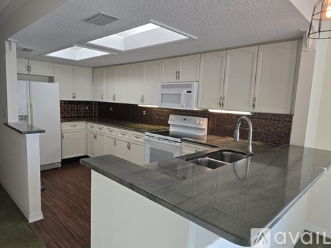 A kitchen with white cabinets and a black countertop.