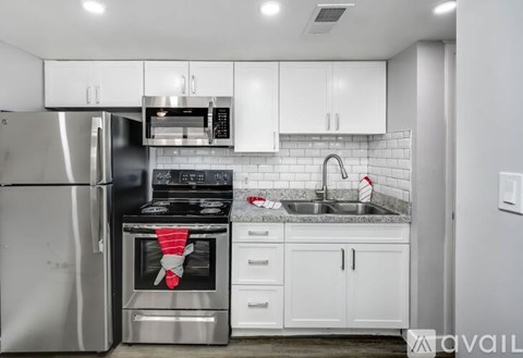 A kitchen with white cabinets and a stainless steel refrigerator.