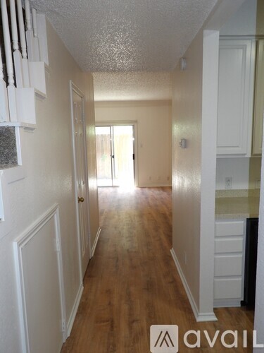 A hallway with a staircase on the left and a door on the right.