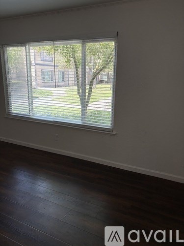 A room with a window showing a tree and a building outside.