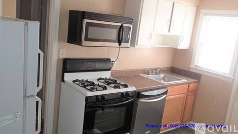 A kitchen with a white refrigerator, black microwave, white stove, and white oven.