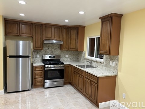 A kitchen with a refrigerator, oven, and sink.