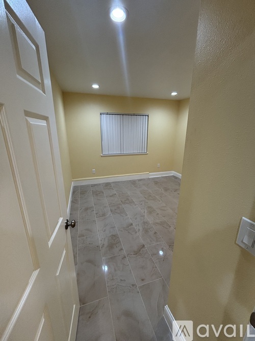 A hallway with a tiled floor and a white door.