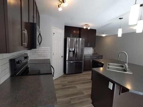 A kitchen with dark brown cabinets and a stainless steel refrigerator.