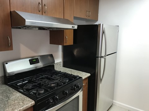 A black stove top oven with a digital display and a black refrigerator in a kitchen.