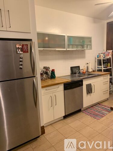 A kitchen with a stainless steel refrigerator and white cabinets.