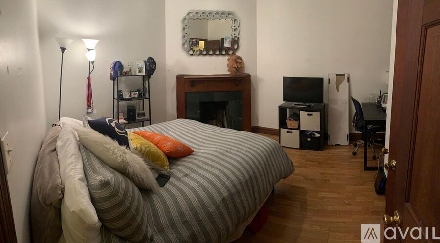 A bedroom with a bed, a fireplace, and a mirror on the wall.