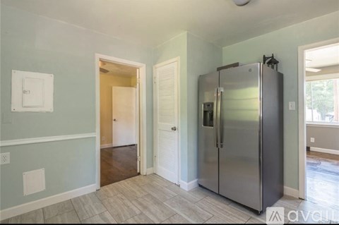 A kitchen with a stainless steel refrigerator and a door open to a hallway.