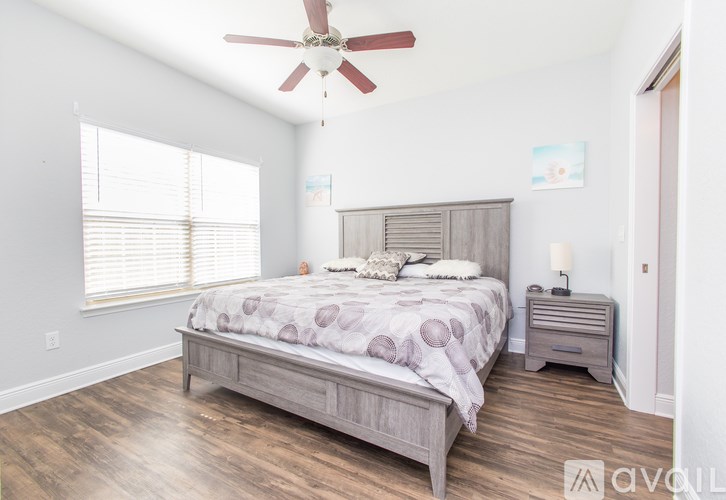 A bedroom with a bed, nightstand, and a ceiling fan.