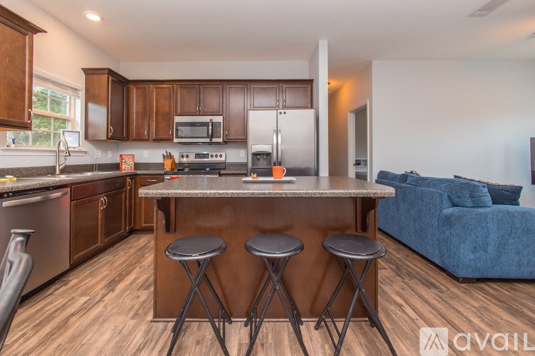 A kitchen with a bar stool and a blue sofa in the living room.
