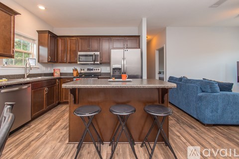 A kitchen with a bar stool and a blue sofa in the living room.