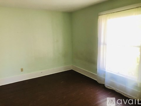 A room with a window and wooden flooring.