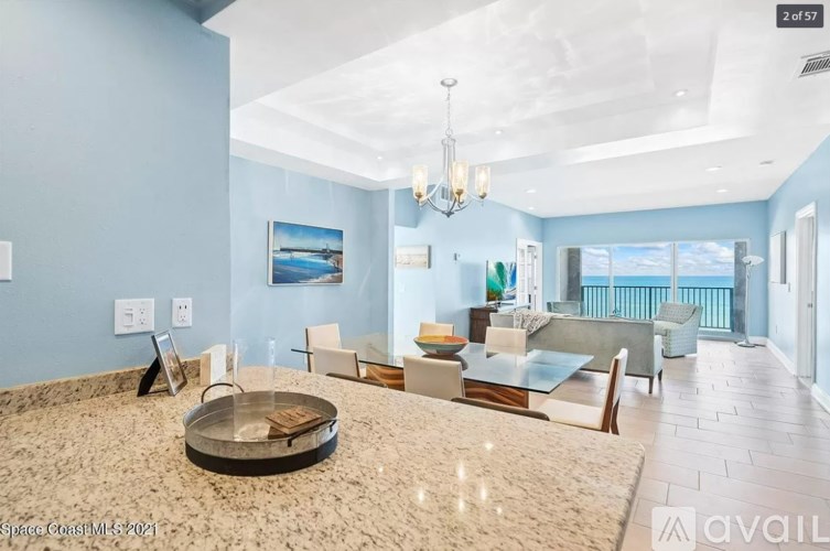 A spacious living room with a large glass table and a chandelier.
