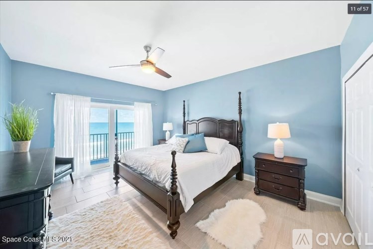 A bedroom with a large bed, a ceiling fan, and a window with curtains.