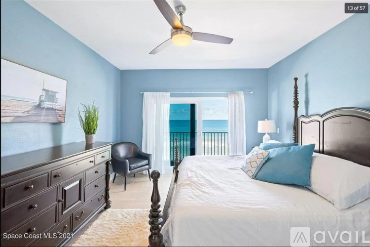A bedroom with a bed, dresser, chair, and a ceiling fan.