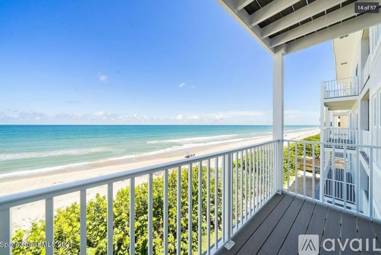 A balcony overlooks a beach with a clear blue sky.