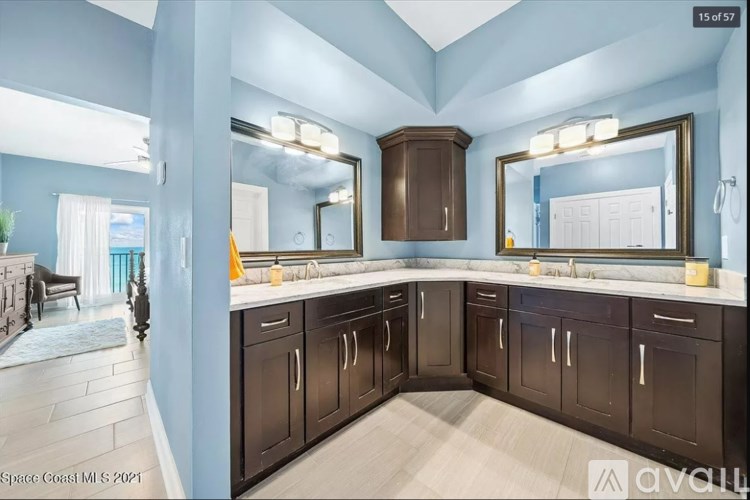 A bathroom with a large mirror and brown cabinets.