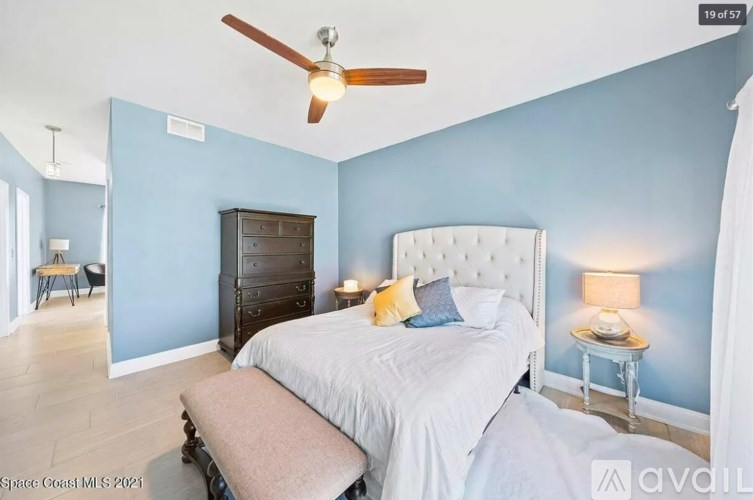 A bedroom with a bed, dresser, and ceiling fan.